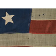 13 HAND-SEWN STARS IN A 3-2-3-2-3 CONFIGURATION OF LINEAL ROWS, ON A LARGE SCALE ANTIQUE AMERICAN FLAG WITH A STENCILED SIGNATURE ALONG THE HOIST THAT READS "GEO L. WRIGHT. BOYLSTON. MA.", PROBABLY MADE FOR THE 100-YEAR ANNIVERSARY OF AMERICAN INDEPENDENCE IN 1876