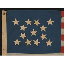 13 HAND-SEWN STARS IN A MEDALLION PATTERN ON A SMALL SCALE FLAG OF THE 1876 CENTENNIAL ERA, WITH A PRUSSIAN BLUE CANTON AND AN ATTRACTIVE PRESENTATION