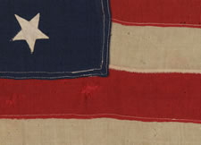 13 HAND-SEWN, UPSIDEDOWN STARS, IN THE 4-5-4 PATTERN, ON AN EXTREMELY SMALL SCALE FLAG WITH ITS CANTON RESTING ON THE "WAR STRIPE", MADE BETWEEN 1864 AND THE 1876 CENTENNIAL OF AMERICAN INDEPENDENCE