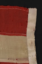 13 HAND-SEWN, UPSIDEDOWN STARS, IN THE 4-5-4 PATTERN, ON AN EXTREMELY SMALL SCALE FLAG WITH ITS CANTON RESTING ON THE "WAR STRIPE", MADE BETWEEN 1864 AND THE 1876 CENTENNIAL OF AMERICAN INDEPENDENCE