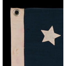 13 SLIGHTLY BULBOUS STARS IN A MEDALLION CONFIGURATION, WITH A LARGE CENTER STAR, ON A SMALL-SCALE ANTIQUE AMERICAN FLAG MADE DURING THE LAST DECADE OF THE 19TH CENTURY, CA 1890-1895