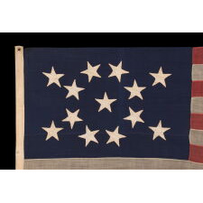 13 STAR ANTIQUE AMERICAN FLAG WITH HAND-SEWN STARS IN AN UNUSUAL, ELONGATED FORM OF THE MEDALLION CONFIGURATION AND ENDEARING WEAR FROM LONG-TERM USE, MADE IN THE ERA OF THE 1876 CENTENNIAL OF AMERICAN INDEPENDENCE