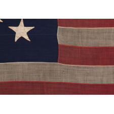 13 STAR ANTIQUE AMERICAN FLAG WITH HAND-SEWN STARS IN AN UNUSUAL, ELONGATED FORM OF THE MEDALLION CONFIGURATION AND ENDEARING WEAR FROM LONG-TERM USE, MADE IN THE ERA OF THE 1876 CENTENNIAL OF AMERICAN INDEPENDENCE