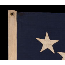 13 STAR ANTIQUE AMERICAN FLAG WITH HAND-SEWN STARS IN AN UNUSUAL, ELONGATED FORM OF THE MEDALLION CONFIGURATION AND ENDEARING WEAR FROM LONG-TERM USE, MADE IN THE ERA OF THE 1876 CENTENNIAL OF AMERICAN INDEPENDENCE