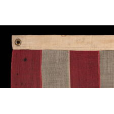 13 STAR ANTIQUE AMERICAN FLAG WITH HAND-SEWN STARS IN AN UNUSUAL, ELONGATED FORM OF THE MEDALLION CONFIGURATION AND ENDEARING WEAR FROM LONG-TERM USE, MADE IN THE ERA OF THE 1876 CENTENNIAL OF AMERICAN INDEPENDENCE