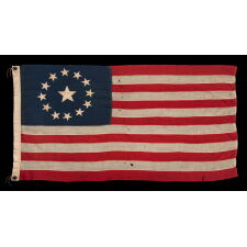 13 STAR ANTIQUE AMERICAN FLAG, WITH A CIRCULAR ARRANGEMENT OF WHAT IS KNOWN AS THE 3RD MARYLAND PATTERN, ON A SMALL SCALE EXAMPLE WITH BEAUTIFUL, ELONGATED PROPORTIONS AND AN UNUSUALLY LARGE CENTER STAR, MADE CIRCA 1890-1900