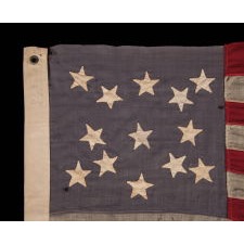 13 STAR FLAG WITH A MEDALLION CONFIGURATION OF HAND-SEWN STARS ON A DUSTY BLUE CANTON; A SMALL-SCALE ANTIQUE AMERICAN FLAG OF THE LATE 19TH CENTURY: