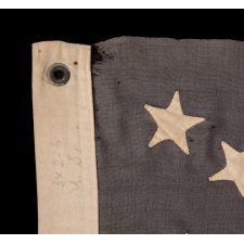 13 STAR FLAG WITH A MEDALLION CONFIGURATION OF HAND-SEWN STARS ON A DUSTY BLUE CANTON; A SMALL-SCALE ANTIQUE AMERICAN FLAG OF THE LATE 19TH CENTURY: