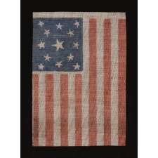 13 STARS IN A MEDALLION PATTERN ON AN ANTIQUE AMERICAN PARADE FLAG, MADE FOR THE 1876 CENTENNIAL OF AMERICAN INDEPENDENCE; A SCARCE EXAMPLE AMONG ITS COUNTERPARTS, WITH NICE FOLK QUALITIES