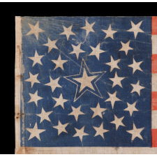 31 STARS ON AN ANTIQUE AMERICAN FLAG WITH ITS STARS CONFIGURED IN A MEDALLION PATTERN THAT FEATURES A LARGE, HALOED CENTER STAR; REFLECTS THE PERIOD WHEN CALIFORNIA HAD RECENTLY BECOME THE 31ST STATE TO ENTER THE UNION, 1850-1858