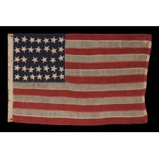 34 HAPHAZARDLY PLACED, HAND-SEWN STARS, IN CRUDE LINEAL ROWS, ON AN ANTIQUE AMERICAN FLAG OF THE CIVIL WAR PERIOD WITH HAND-SEWN STRIPES AND IN A TINY SCALE AMONG ITS COUNTERPARTS, 1861-1863, REFLECTS THE ADDITION OF KANSAS AS THE 34TH STATE