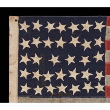 34 HAPHAZARDLY PLACED, HAND-SEWN STARS, IN CRUDE LINEAL ROWS, ON AN ANTIQUE AMERICAN FLAG OF THE CIVIL WAR PERIOD WITH HAND-SEWN STRIPES AND IN A TINY SCALE AMONG ITS COUNTERPARTS, 1861-1863, REFLECTS THE ADDITION OF KANSAS AS THE 34TH STATE