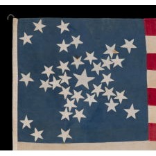 34 STARS ON A CORNFLOWER BLUE CANTON, ARRANGED IN A BEAUTIFUL VARIANT OF THE "GREAT STAR" PATTERN, ON AN ENTIRELY HAND-SEWN ANTIQUE AMERICAN MADE DURING THE OPENING YEARS OF THE CIVIL WAR, 1861-63, IN AN EXTREMELY SMALL AND DESIRABLE SCALE FOR THE PERIOD