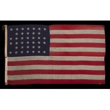 38 STARS IN A NOTCHED, CROSSHATCH PATTERN ON AN ANTIQUE AMERICAN FLAG MADE BY THE U.S. BUNTING COMPANY IN LOWELL, MASSACHUSETTS, SIGNED "TORREY," REFLECTS THE ERA OF COLORADO STATEHOOD, CIRCA 1876-1889