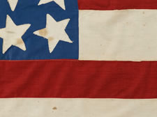 39 STARS IN A LINEAL PATTERN WITH A HUGE, HALOED CENTER STAR AND DYNAMIC VISUAL FEATURES, ITS CANTON RESTING ON THE WAR STRIPE, PROBABLY MADE FOR THE 1876 CENTENNIAL OF AMERICAN INDEPENDENCE, NEVER AN OFFICIAL STAR COUNT, REFLECTS THE ANTICIPATED ARRIVAL OF COLORADO AND THE DAKOTA TERRITORY