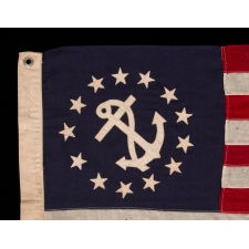 ANTIQUE AMERICAN PRIVATE YACHT FLAG (ENSIGN) WITH 13 STARS SURROUNDING A CANTED ANCHOR, AN ATTRACTIVE, ELONGATED EXAMPLE WITH AN OFF-SET DEVICE, CIRCA 1905 – 1920