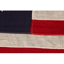 ANTIQUE AMERICAN PRIVATE YACHT FLAG (ENSIGN) WITH 13 STARS SURROUNDING A CANTED ANCHOR, AN ATTRACTIVE, ELONGATED EXAMPLE WITH AN OFF-SET DEVICE, CIRCA 1905 – 1920