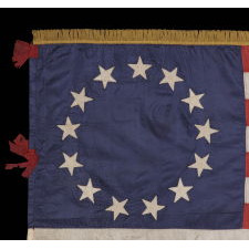 BEAUTIFULLY GRAPHIC AND HIGHLY UNORDINARY 13 STAR FLAG IN THE BETSY ROSS PATTERN, A MADE OF FINE SILK WITH SILK FRINGE AND TIES, IN A TINY SIZE AMONG ITS COUNTERPARTS CA 1895-1926