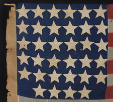 ENTIRELY HAND-SEWN 34 STAR FLAG OF THE CIVIL WAR PERIOD WITH A GREAT EARLY APPEARANCE, A WIDE LINEN SLEEVE, AND A VERY UNUSUAL ARRANGEMENT OF UNCOMMONLY LARGE STARS, 1861-63