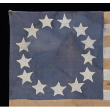 HOMEMADE FLAG WITH 13 STARS ARRANGED IN THE CIRCULAR WREATH PATTERN OFTEN ATTRIBUTED TO BETSY ROSS, WITH ENDEARING WEAR, AND WITH ITS CANTON RESTING ON THE WAR STRIPE, CA 1890-1920's