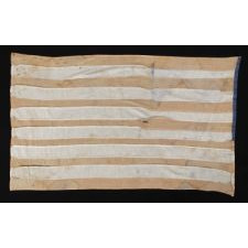 HOMEMADE FLAG WITH 13 STARS ARRANGED IN THE CIRCULAR WREATH PATTERN OFTEN ATTRIBUTED TO BETSY ROSS, WITH ENDEARING WEAR, AND WITH ITS CANTON RESTING ON THE WAR STRIPE, CA 1890-1920's