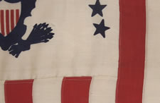 RARE REVENUE CUTTER SERVICE FLAG WITH A BLUE EAGLE AMID AN ARCH OF 13 BLUE STARS ON A WHITE FIELD AND 16 VERTICAL RED AND WHITE STRIPES, CA 1900-1915