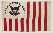 RARE REVENUE CUTTER SERVICE FLAG WITH A BLUE EAGLE AMID AN ARCH OF 13 BLUE STARS ON A WHITE FIELD AND 16 VERTICAL RED AND WHITE STRIPES, CA 1900-1915