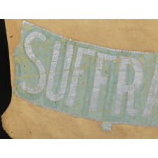 SHIELD-SHAPED BANNER FROM THE NORTH JERSEY SHORE WOMAN'S SUFFRAGE LEAGUE, HANDED DOWN THROUGH THE FAMILY OF ITS PRESIDENT, VIOLA AGUERO, WITH A LARGE ARCHIVE OF MATERIAL THAT INCLUDES AN IMAGE OF HER ACTUALLY HOLDING THE BANNER