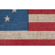 13 STAR ANTIQUE AMERICAN PARADE FLAG WITH A SINGLE WREATH OF STARS REMINISCENT OF THE BETSY ROSS PATTERN, BUT RENDERED AS MORE OF AN OVAL, THE ONLY EXAMPLE OF THIS EXACT VARIETY THAT I HAVE EVER ENCOUNTERED, MADE circa 1890-WWI (U.S. INVOLVEMENT 1917-18)