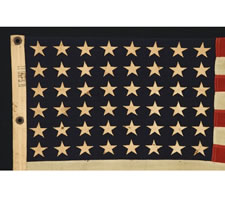 WWII BATTLE FLAG FROM THE U.S.S. FLINT WITH 48 STARS, BROUGHT HOME BY FIREMAN 2ND CLASS F. W. PERRINE, EMBROIDERED WITH HIS NAME, THE SHIP'S NAME, AND DATES OF SERVICE