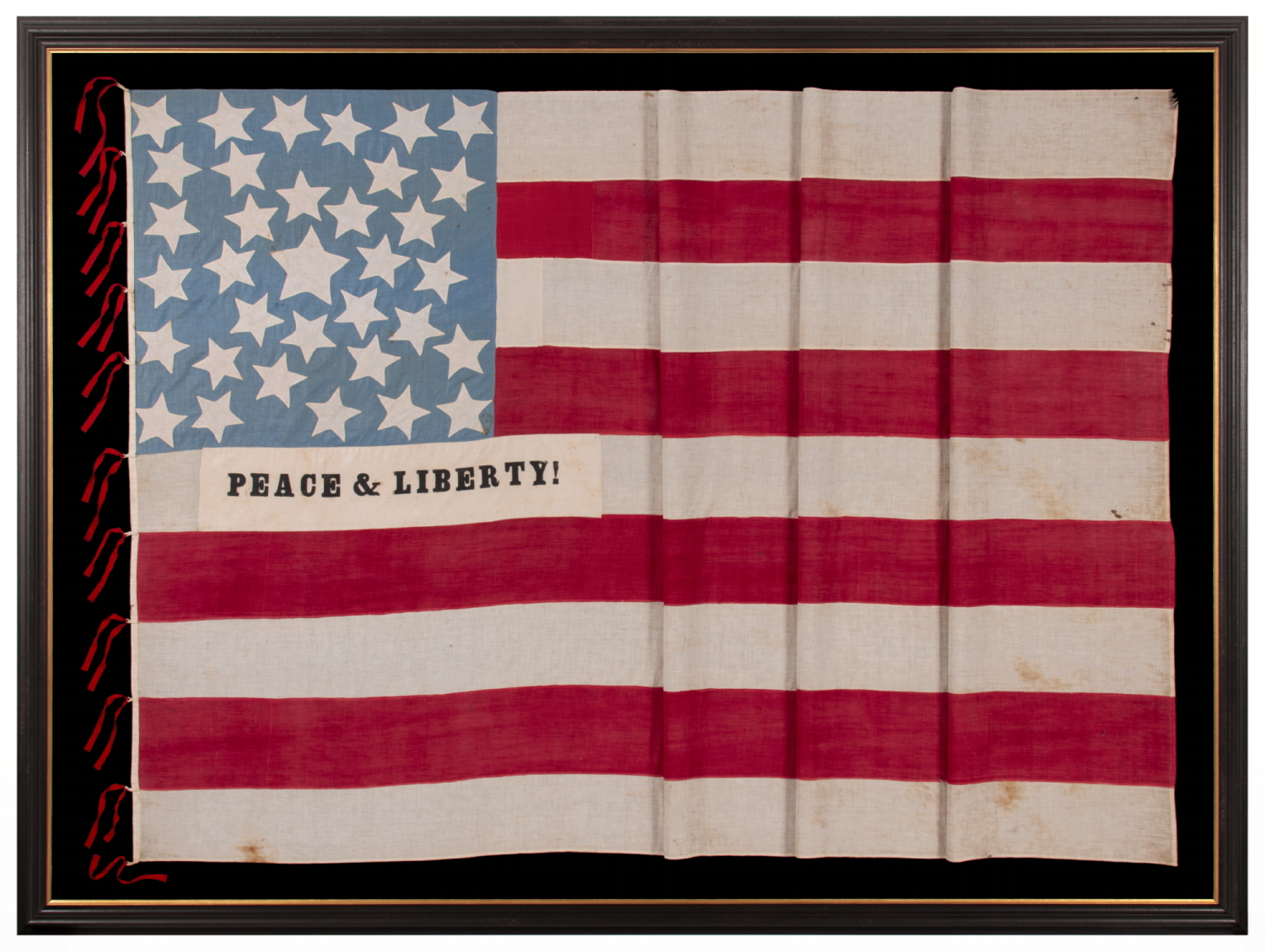 EXCEPTIONAL 34 STAR ANTIQUE AMERICAN CIVIL WAR FLAG WITH A CORNFLOWER BLUE CANTON, HOMEMADE & ENTIRELY HAND-SEWN ca 1861-63, WITH STRIPES THAT BEGIN & END ON WHITE, IN A COUNT OF 9 TO OMIT THE 4 SECEDED STATES FROM AMONG THE ORIGINAL 13 COLONIES, AND WITH APPLIED PANELS THAT READ: “PEACE & LIBERTY”; GIVEN TO DAVIS CAMRON OF “D” Co., 38th OH VOL. BY THE FAMILY OF ORRIN TAYLOR OF “D” & “F” Co.'s, 67th OH INFT'Y, MORTALLY WOUNDED AT APPOMATTOX ON THE VERY DAY OF LEE'S SURRENDER