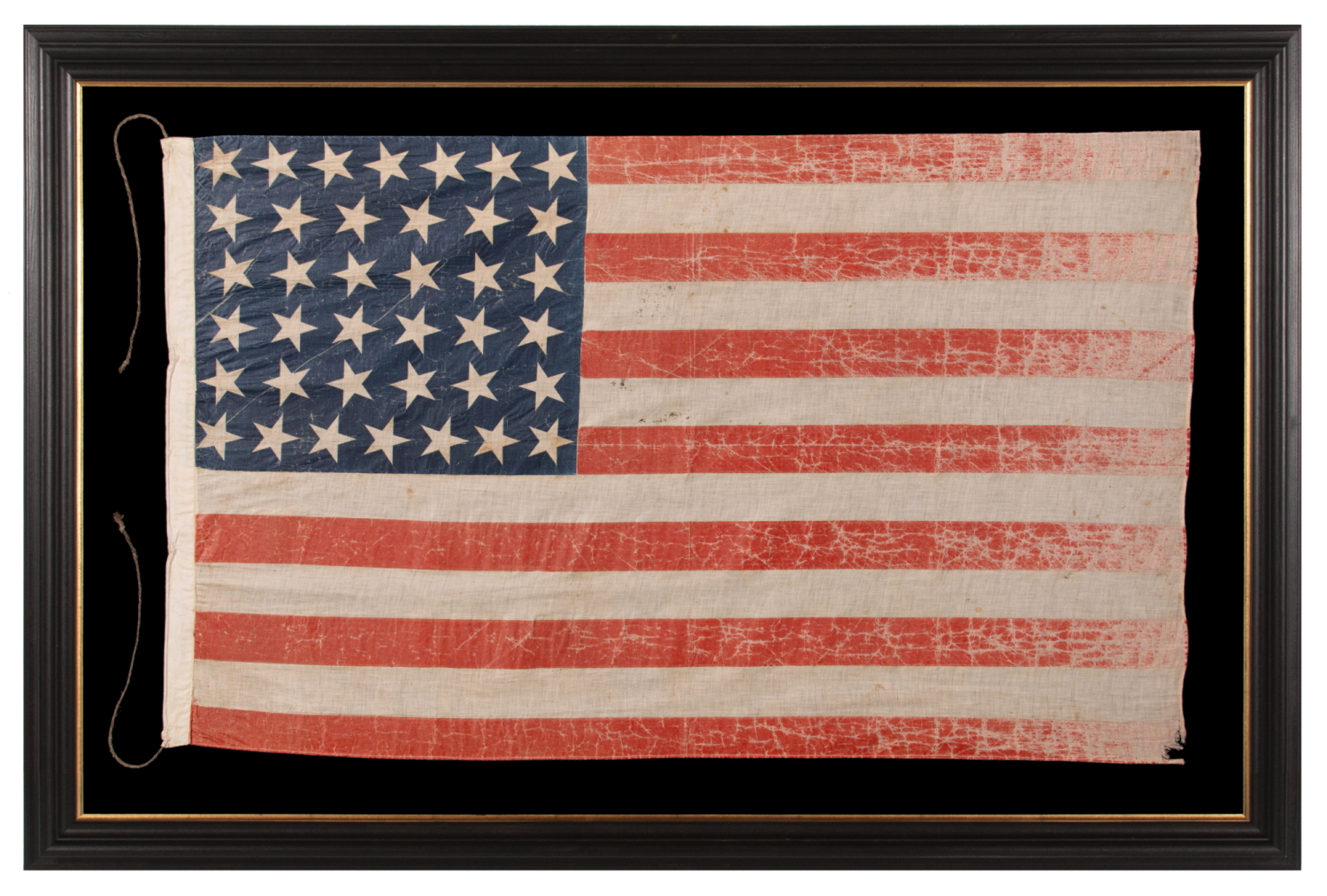 38 STAR ANTIQUE AMERICAN PARADE FLAG IN AN UNUSUALLY LARGE SCALE, WITH ENDEARING WAR FROM OBVIOUS LONG-TERM USE, AND WITH DANCING ROWS IN AN HOURGLASS FORMATION; COLORADO STATEHOOD, 1876-1889