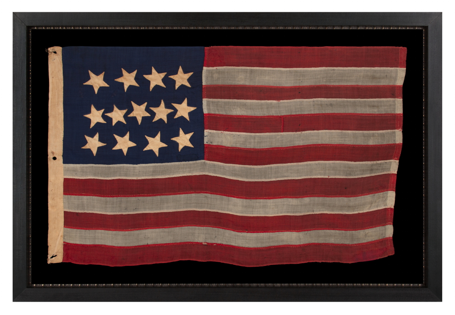 ANTIQUE AMERICAN FLAG WITH A WHIMSICAL PRESENTATION OF 13 STARS IN THE 4-5-4 PATTERN, A VERY EARLY EXAMPLE, MADE circa 1835-1850’s, BOLDY GRAPHIC, ENTIRELY HAND-SEWN AND IN A TINY SCALE AMONG ITS COUNTERPARTS, PROBABLY A U.S. NAVY SMALL BOAT ENSIGN