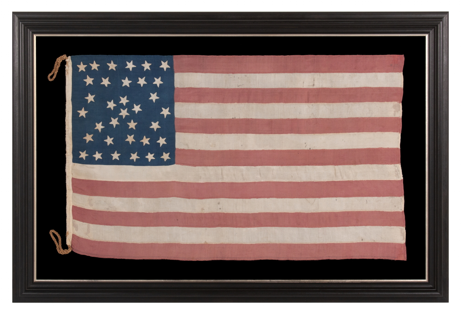 EXTRAORDINARY 34 STAR ANTIQUE AMERICAN FLAG WITH AN ACCORDION OR HOURGLASS MEDALLION CONFIGURATION THAT SURROUNDS A PENTAGON OF STARS IN THE CENTER; MADE OF FINE SILK AND ENTIRELY HAND-SEWN; MADE DURING THE OPENING YEARS OF THE CIVIL WAR (1861-63), IN A TINY SIZE AMONG ITS COUNTERPARTS OF THE PERIOD; REFLECTS THE ADDITION OF KANSAS AS THE 34TH STATE