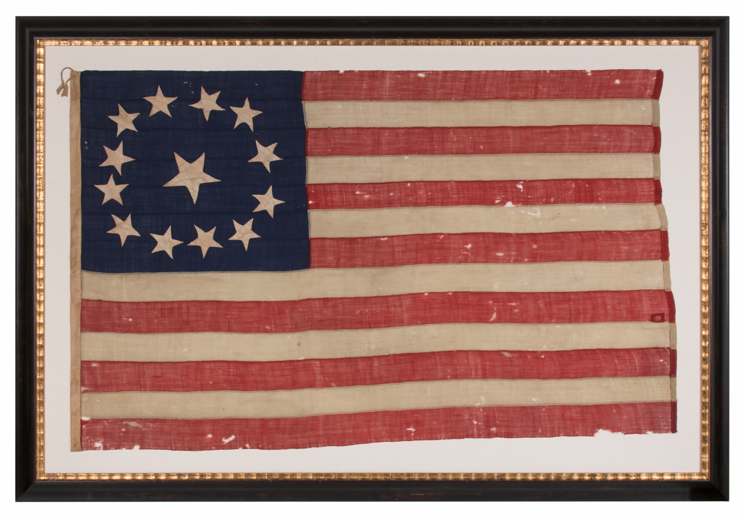 13 STAR ANTIQUE AMERICAN FLAG WITH A CIRCULAR VERSION OF WHAT IS KNOWN AS THE 3RD MARYLAND PATTERN, ENTIRELY HAND-SEWN, WITH ESPECIALLY LARGE STARS SURROUNDING AN EVEN LARGER CENTER STAR; MADE SOMETIME BETWEEN 1850 AND THE CIVIL WAR (1861-65), AN EXCEPTIONAL EXAMPLE WITH WONDERFUL FOLK QUALITIES