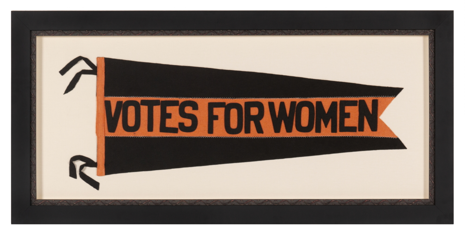 LARGE, SWALLOWTAILED, SUFFRAGETTE PENNANT IN A BLACK & ORANGE COLOR COMBINATION UNIQUE TO THIS EXAMPLE, WITH APPLIED LETTERING THAT READS "VOTES FOR WOMEN” DOWN A WIDE, CENTRAL STRIPE, CIRCA 1912-1920