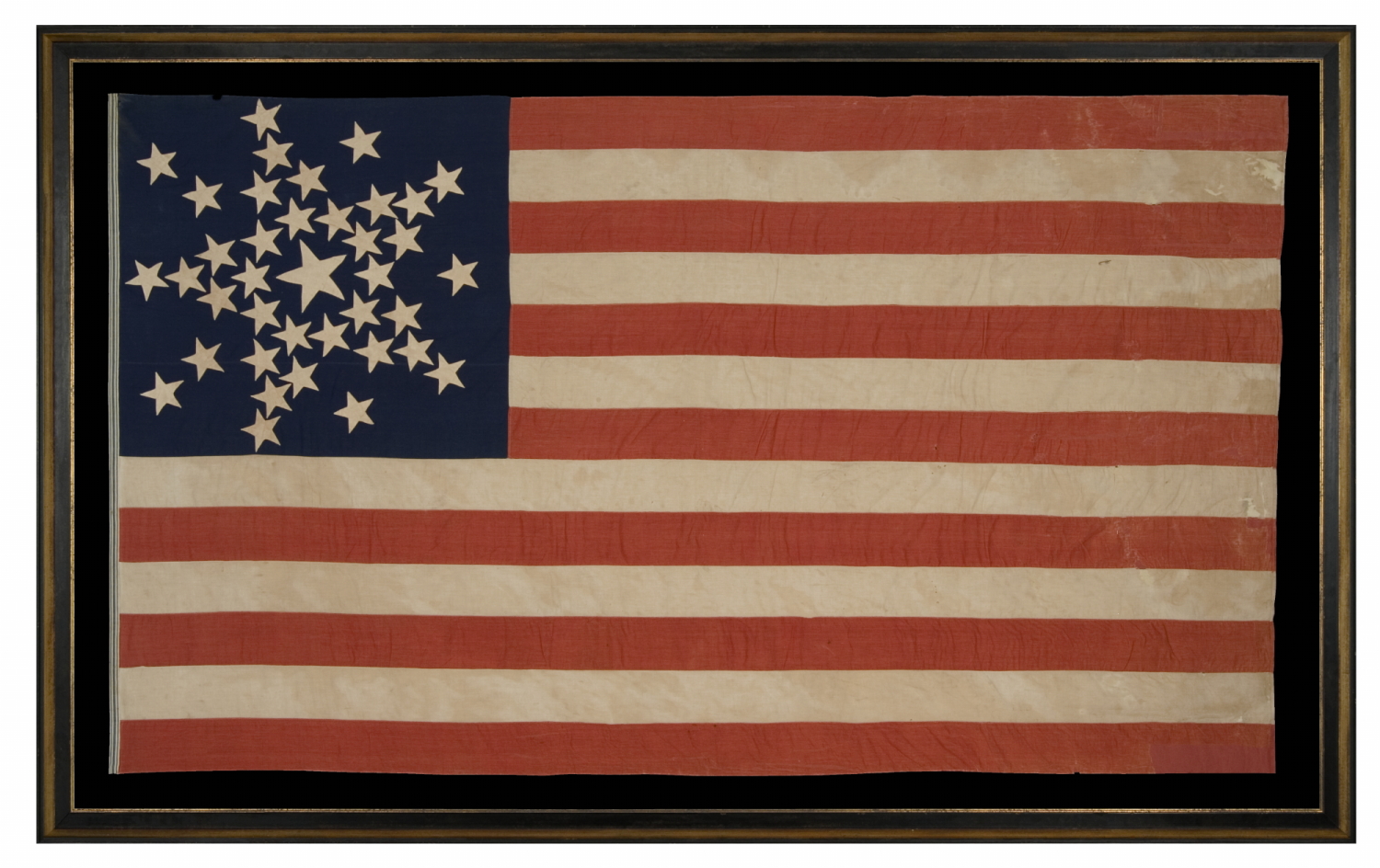 SPECTACULAR 38 STAR ANTIQUE AMERICAN FLAG WITH A RARE VARIANT OF THE "GREAT STAR" PATTERN THAT INCLUDES A STAR BETWEEN EACH ARM, LIKELY MADE FOR THE 1876 CENTENNIAL OF AMERICAN INDEPENDENCE, REFLECTS THE ADDITION OF COLORADO AS THE CENTENNIAL STATE, 1876-1889