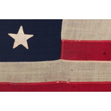 13 STAR ANTIQUE AMERICAN FLAG, MADE IN THE ERA OF THE 1876 CENTENNIAL, WITH HAND-SEWN STARS IN A MEDALLION CONFIGURATION, IN A WONDERFUL, SMALL SCALE AMONG ITS COUNTERPARTS OF THE PERIOD