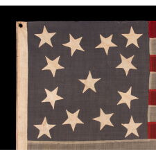 13 STAR ANTIQUE AMERICAN FLAG WITH A DUSTY BLUE CANTON, MADE IN THE ERA OF THE 1876 CENTENNIAL, IN AN INTERESTING CONFIGURATION THAT FEATURES TRIOS OF STARS IN EACH CORNER AND A SINGLE, CENTER STAR; A RARE VARIANT THAT I CLASSIFY “TRI-CORNER HAT” MEDALLION