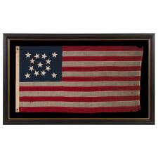 13 STAR ANTIQUE AMERICAN FLAG WITH A MEDALLION CONFIGURATION OF HAND-SEWN STARS AND A BEAUTIFUL, ELONGATED PROFILE, MADE IN THE ERA OF THE 1876 CENTENNIAL OF AMERICAN INDEPENDENCE, IN AN UNCOMMONLY SMALL SIZE AMONG ITS COUNTERPARTS OF THE PERIOD WITH SEWN CONSTRUCTION