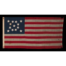 13 STAR ANTIQUE AMERICAN FLAG WITH A MEDALLION CONFIGURATION OF HAND-SEWN STARS AND A BEAUTIFUL, ELONGATED PROFILE, MADE IN THE ERA OF THE 1876 CENTENNIAL OF AMERICAN INDEPENDENCE, IN AN UNCOMMONLY SMALL SIZE AMONG ITS COUNTERPARTS OF THE PERIOD WITH SEWN CONSTRUCTION