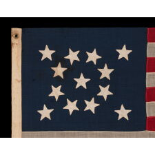 13 STAR ANTIQUE AMERICAN FLAG WITH A MEDALLION CONFIGURATION OF HAND-SEWN STARS AND A BEAUTIFUL, ELONGATED PROFILE, MADE IN THE ERA OF THE 1876 CENTENNIAL OF AMERICAN INDEPENDENCE, IN AN UNCOMMONLY SMALL SIZE AMONG ITS COUNTERPARTS OF THE PERIOD WITH SEWN CONSTRUCTION