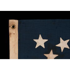 13 STAR ANTIQUE AMERICAN FLAG WITH A MEDALLION CONFIGURATION OF HAND-SEWN STARS AND A BEAUTIFUL, ELONGATED PROFILE, MADE IN THE ERA OF THE 1876 CENTENNIAL OF AMERICAN INDEPENDENCE, IN AN UNCOMMONLY SMALL SIZE AMONG ITS COUNTERPARTS OF THE PERIOD WITH SEWN CONSTRUCTION