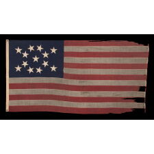 13 STAR ANTIQUE AMERICAN FLAG WITH HAND-SEWN STARS IN AN UNUSUAL, ELONGATED FORM OF THE MEDALLION CONFIGURATION AND ENDEARING WEAR FROM LONG-TERM USE, MADE IN THE ERA OF THE 1876 CENTENNIAL OF AMERICAN INDEPENDENCE