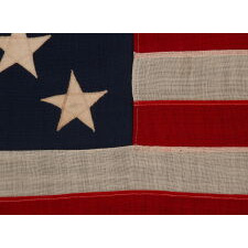 13 STAR ANTIQUE AMERICAN FLAG WITH A 3-2-3-2-3 CONFIGURATION OF STARS; A SMALL-SCALE EXAMPLE, MADE IN THE 1895-1926 ERA, MARKED “R.H. MACY & CO.”