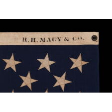 13 STAR ANTIQUE AMERICAN FLAG WITH A 3-2-3-2-3 CONFIGURATION OF STARS; A SMALL-SCALE EXAMPLE, MADE IN THE 1895-1926 ERA, MARKED “R.H. MACY & CO.”