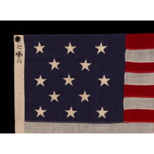 13 STAR ANTIQUE AMERICAN FLAG WITH A 3-2-3-2-3 CONFIGURATION OF STARS ON AN ATTRACTIVE, INDIGO BLUE CANTON; A SMALL-SCALE EXAMPLE OF THE 1895-1926 ERA, INSCRIBED WITH THE SURNAME “SPENGE,” LIKELY PRODUCED BY A MAKER WITH LINKS TO THE U.S. ARMY’S 19th CORPS