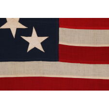 13 STAR ANTIQUE AMERICAN FLAG WITH A 3-2-3-2-3 PATTERN OF ESPECIALLY LARGE STARS; A U.S. NAVY SMALL BOAT ENSIGN, ALMOST CERTAINLY MADE AT MARE ISLAND, CALIFORNIA, circa 1906-1912, LARGER THAN THE SPECIFIED DIMENSIONS & UNCHARACTERISTICALLY UNSIGNED; EXTREMELY RARE
