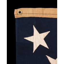 13 STAR ANTIQUE AMERICAN FLAG WITH A 3-2-3-2-3 PATTERN OF ESPECIALLY LARGE STARS; A U.S. NAVY SMALL BOAT ENSIGN, ALMOST CERTAINLY MADE AT MARE ISLAND, CALIFORNIA, circa 1906-1912, LARGER THAN THE SPECIFIED DIMENSIONS & UNCHARACTERISTICALLY UNSIGNED; EXTREMELY RARE