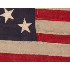 13 STAR ANTIQUE AMERICAN FLAG WITH A MEDALLION CONFIGURATION OF STARS; A TINY EXAMPLE AMONG ITS COUNTERPARTS WITH SEWN CONSTRUCTION, MADE circa 1895-1926, EXHIBITED AT THE MUSEUM OF THE AMERICAN REVOLUTION, JUNE-JULY 2019